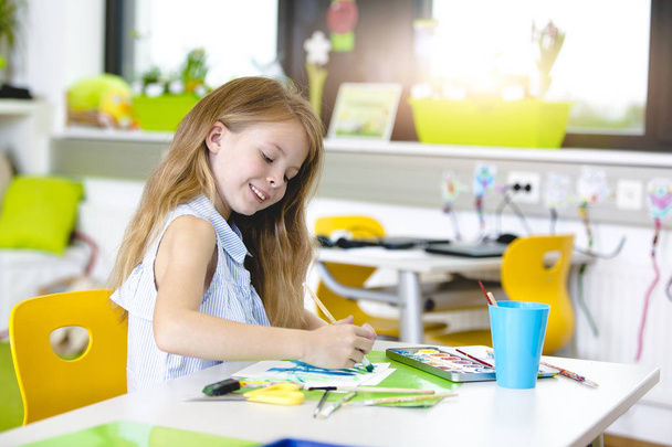 At school - pretty schoolgirl is drawing in painting lessons - Φωτογραφία, εικόνα