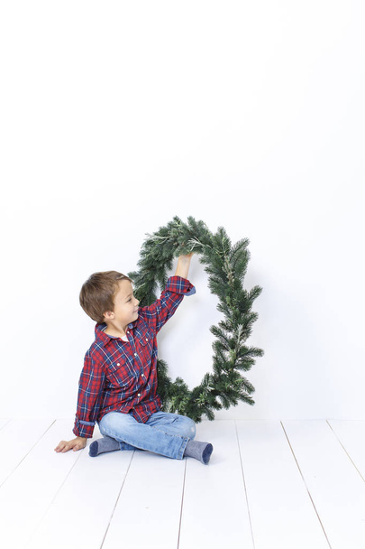 Happy little boy posing with christmas wreath isolated on white background - Valokuva, kuva