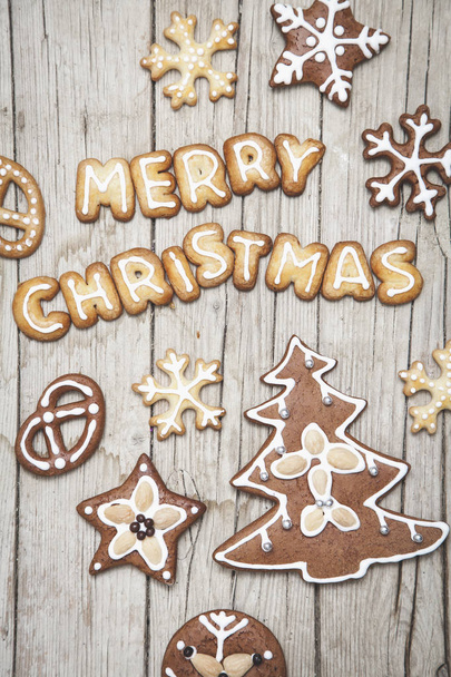 merry Christmas lettering made with gingerbread cookies on wooden tabletop - Photo, image
