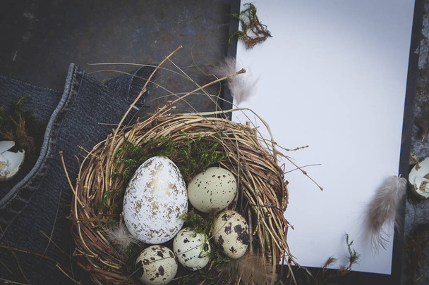 Decoração de Páscoa com ninho e ovos com prancheta em fundo escuro, conceito de férias
   - Foto, Imagem