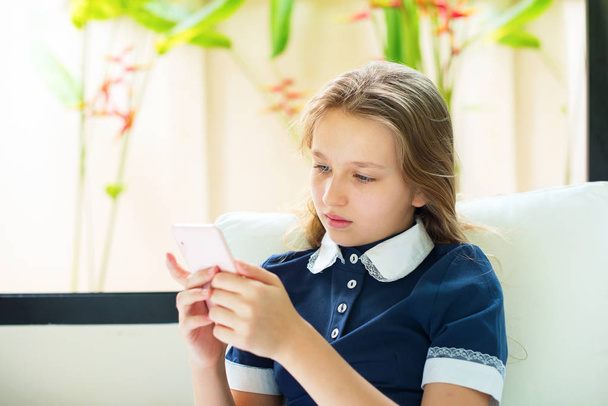 Pretty teenager looking in smartphone sitting on sofa Concept free schooling education Homeschooling - 写真・画像