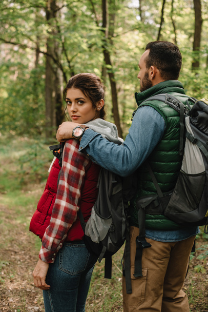 man hugging woman while hiking in forest together - Photo, Image