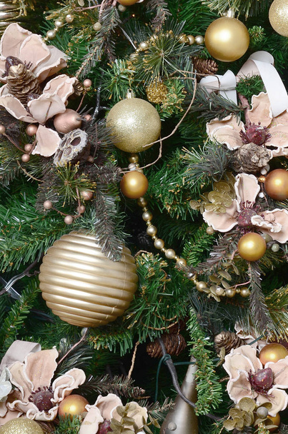 Decorating Christmas tree close up. Decoration bulb, green fir tree, golden x-mas toys and lights. Use for Christmas and New years celebration background - Photo, Image