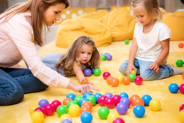 tutor apuntando a las bolas de colores educativos a los niños en el jardín de infantes
 - Foto, Imagen