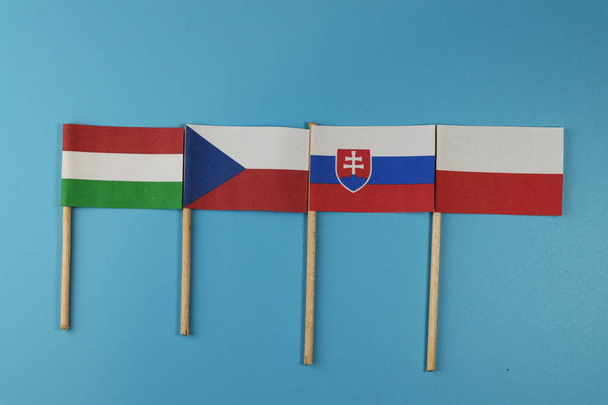 Flagi z członków grupy Wyszehradzkiej cztery drewniane kije na niebieskim tle - Zdjęcie, obraz