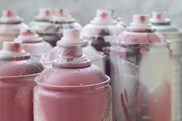 Una gran cantidad de latas de aerosol sucias y usadas de pintura rosa brillante. Fotografía macro con poca profundidad de campo. Enfoque selectivo en la boquilla de pulverización
 - Foto, imagen