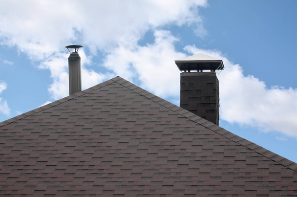 Het dak bedekt met een moderne platte bitumineuze waterdichte coating onder een blauwe hemel - Foto, afbeelding