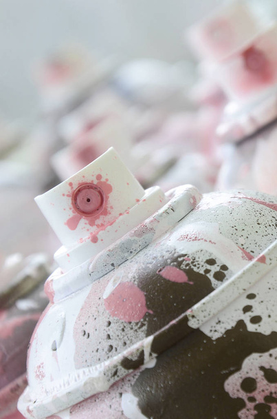 Um monte de latas de aerossol sujas e usadas de tinta rosa brilhante. Fotografia macro com profundidade de campo rasa. Foco seletivo no bico de pulverização
 - Foto, Imagem