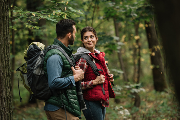 side view of man and woman with backpacks hiking in woods - Photo, Image