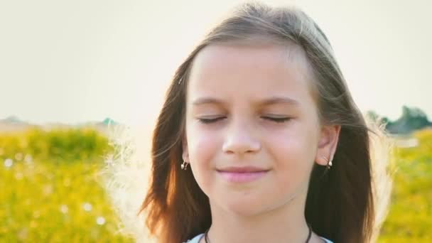 Portrét atraktivní holčička s velkýma očima na pozadí přírody s vývojem vlasy, dítě dívka pokrývá její tvář s rukama před větrem - Záběry, video