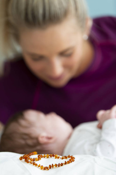 gyönyörű szőke anya az ő 3 hónapos baba visel egy borostyán nyaklánc - Fotó, kép