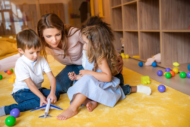 tuteur étreignant adorables enfants sur le tapis à la maternelle
 - Photo, image