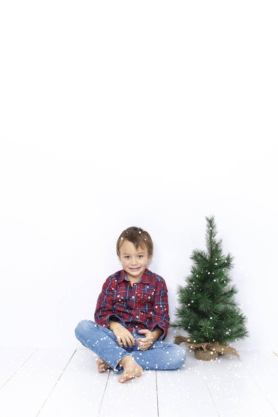 Happy little boy posing near christmas tree isolated on white background - Photo, image