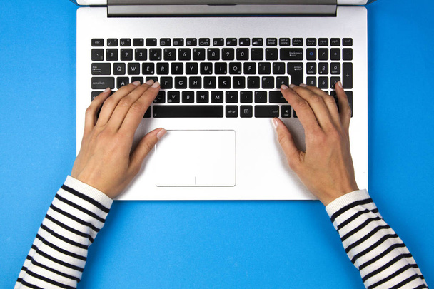 Woman hands typing on laptop computer, blue background - Photo, Image