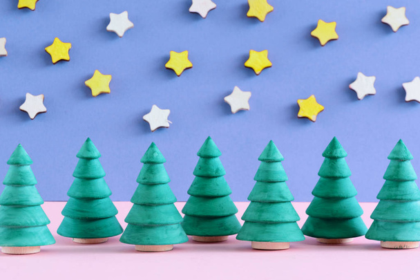Small decorative Christmas trees on pink and blue background with stars. - Fotografie, Obrázek
