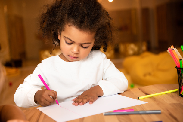 adorable african american child drawing with pink felt pen in kindergarten - Photo, Image