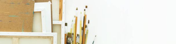 art background from equipment tools for drawing Paints canvases brushes on table Long banner - 写真・画像