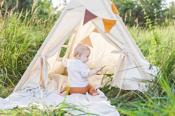 One year cute boy in a teepee outdoors. - Photo, image