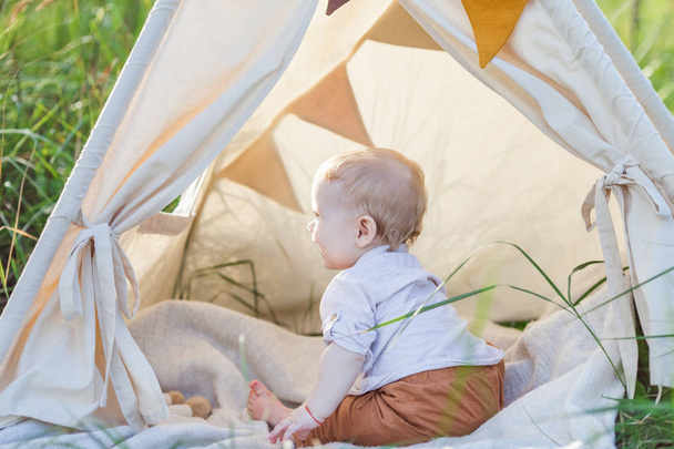 One year cute boy in a teepee outdoors. - Photo, image