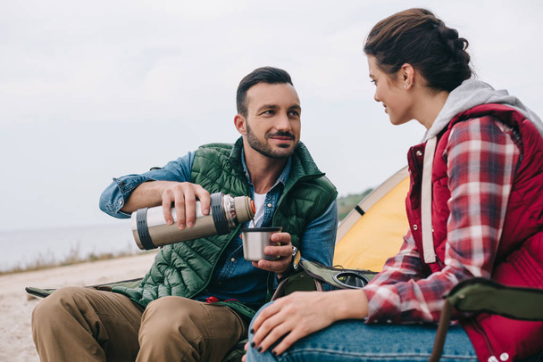 pareja bebiendo té caliente durante el camping
 - Foto, imagen