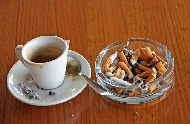 cenicero lleno de colillas de cigarrillo y una taza de espresso
 - Foto, imagen