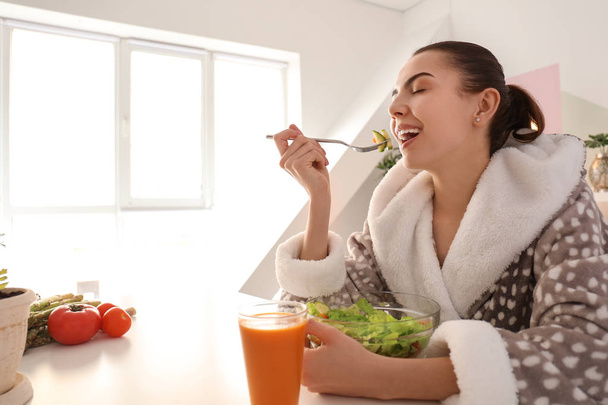 Une jeune femme mange de la salade fraîche à la maison. Concept d'alimentation saine
 - Photo, image