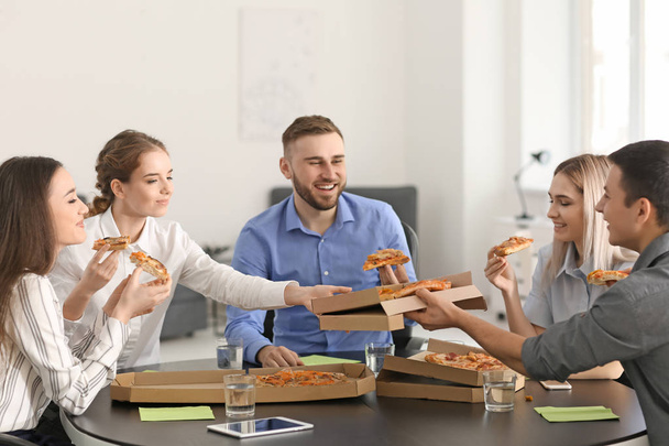 Jóvenes comiendo pizza en la mesa de la oficina
 - Foto, imagen