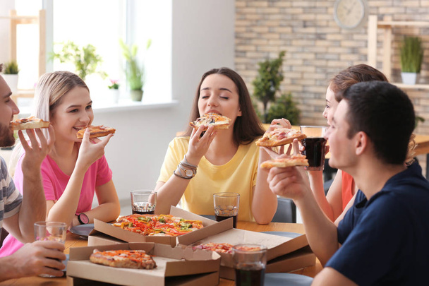 Les jeunes mangent de la pizza à table à l'intérieur
 - Photo, image