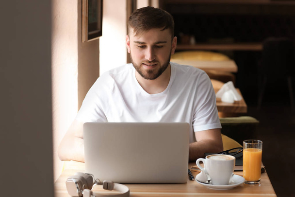 Young freelancer with laptop working in cafe - Zdjęcie, obraz