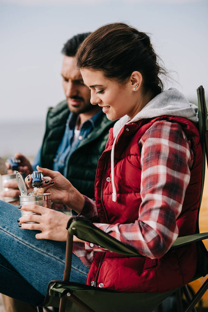 couple eating food from cans while having camping - Foto, imagen