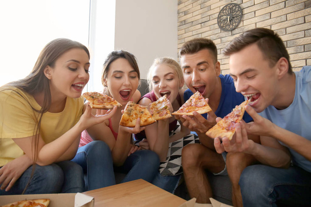 Молодые люди веселятся на вечеринке с вкусной пиццей в помещении
 - Фото, изображение
