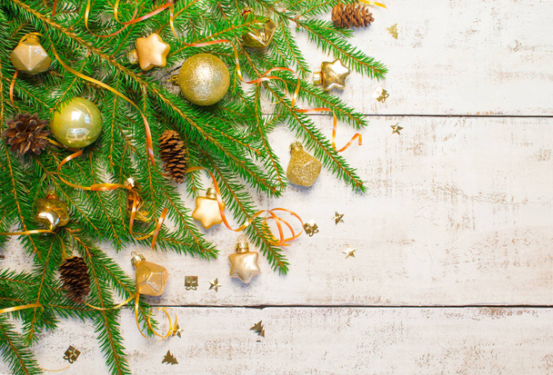 Christmas or New Year background: fir tree branches, gold glass toys, decorations and cones on a white wooden background. - Foto, Imagem