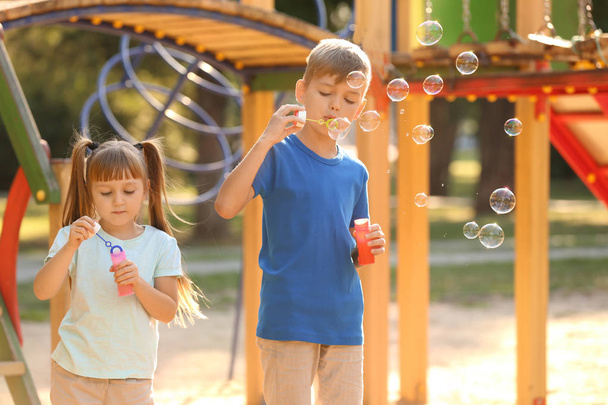 Милые маленькие дети выдувают мыльные пузыри на открытом воздухе
 - Фото, изображение