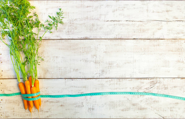 Fresh carrot and measuring tape on wooden table. Healthy food - Φωτογραφία, εικόνα