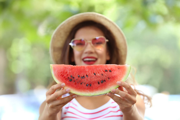 Beautiful young woman with slice of tasty watermelon outdoors - 写真・画像