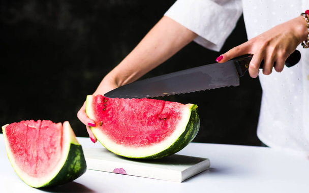 Woman slicing watermelon on a cutting board - Photo, Image