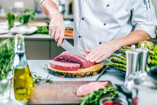 Chef in restaurant kitchen cooking,he is cutting meat or steak  - Fotografie, Obrázek