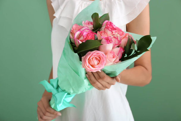 Mujer sosteniendo ramo de hermosas rosas sobre fondo de color
 - Foto, Imagen