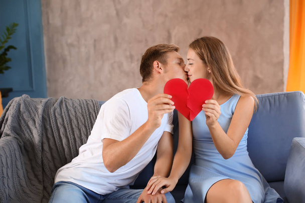 Nuori pari yhdistää puolikkaat särkynyt sydän sohvalla kotona
 - Valokuva, kuva