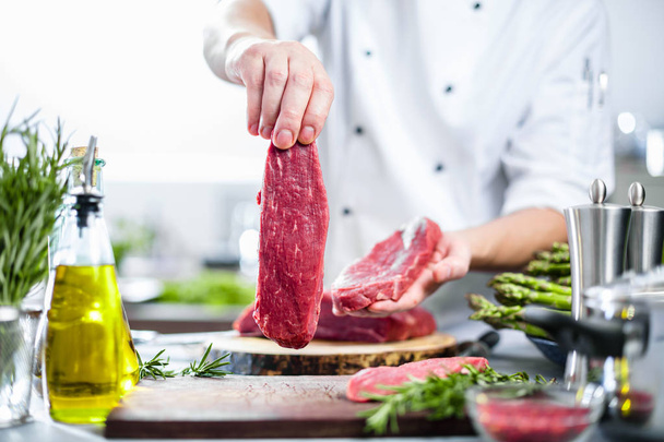 Chef in restaurant kitchen cooking,he is cutting meat or steak  - Foto, Bild
