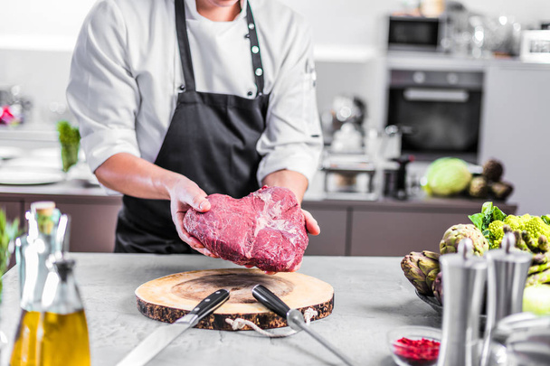 Chef in restaurant kitchen cooking,he is cutting meat or steak  - Fotografie, Obrázek