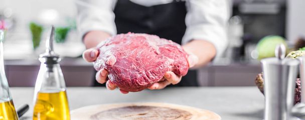 Chef in restaurant kitchen cooking,he is cutting meat or steak  - Foto, Bild