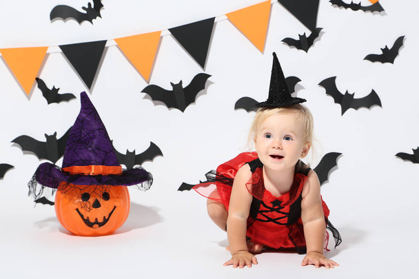 Baby girl in halloween costume with plastic pumpkin on white background - Foto, Imagen