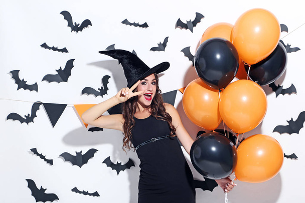 Young woman in halloween costume with balloons on white background - Foto, Imagen