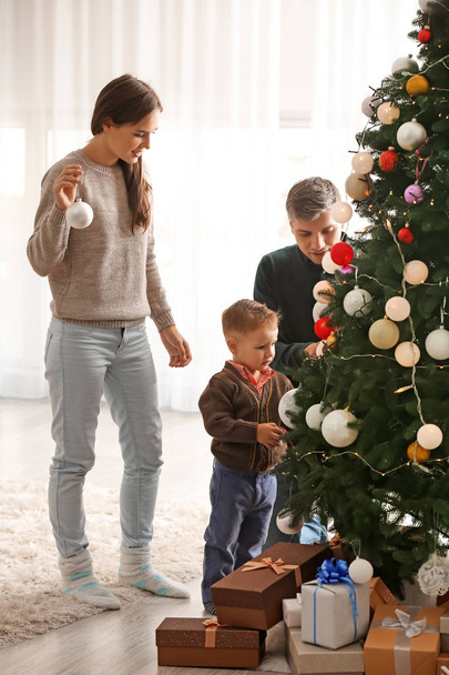 Family decorating beautiful Christmas tree in room - Photo, Image