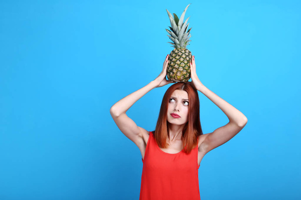 Beautiful redhaired woman with pineapple on blue background - Foto, imagen