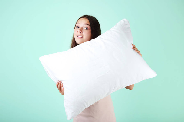 Young girl with white pillow on mint background - Photo, image