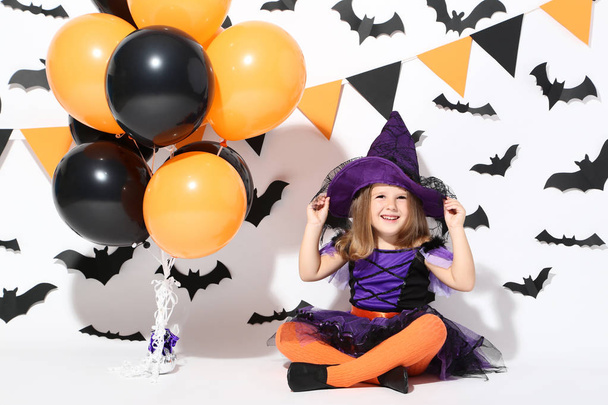Young girl in halloween costume with balloons on white background - 写真・画像