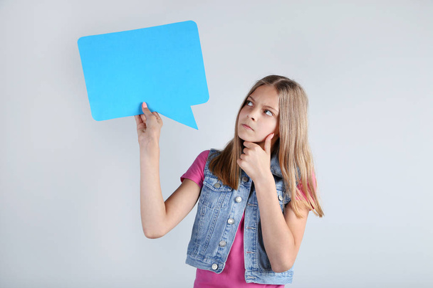 Young girl holding speech bubble on grey background - Photo, image