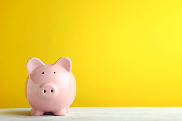 Pink piggy bank on yellow background - Foto, afbeelding